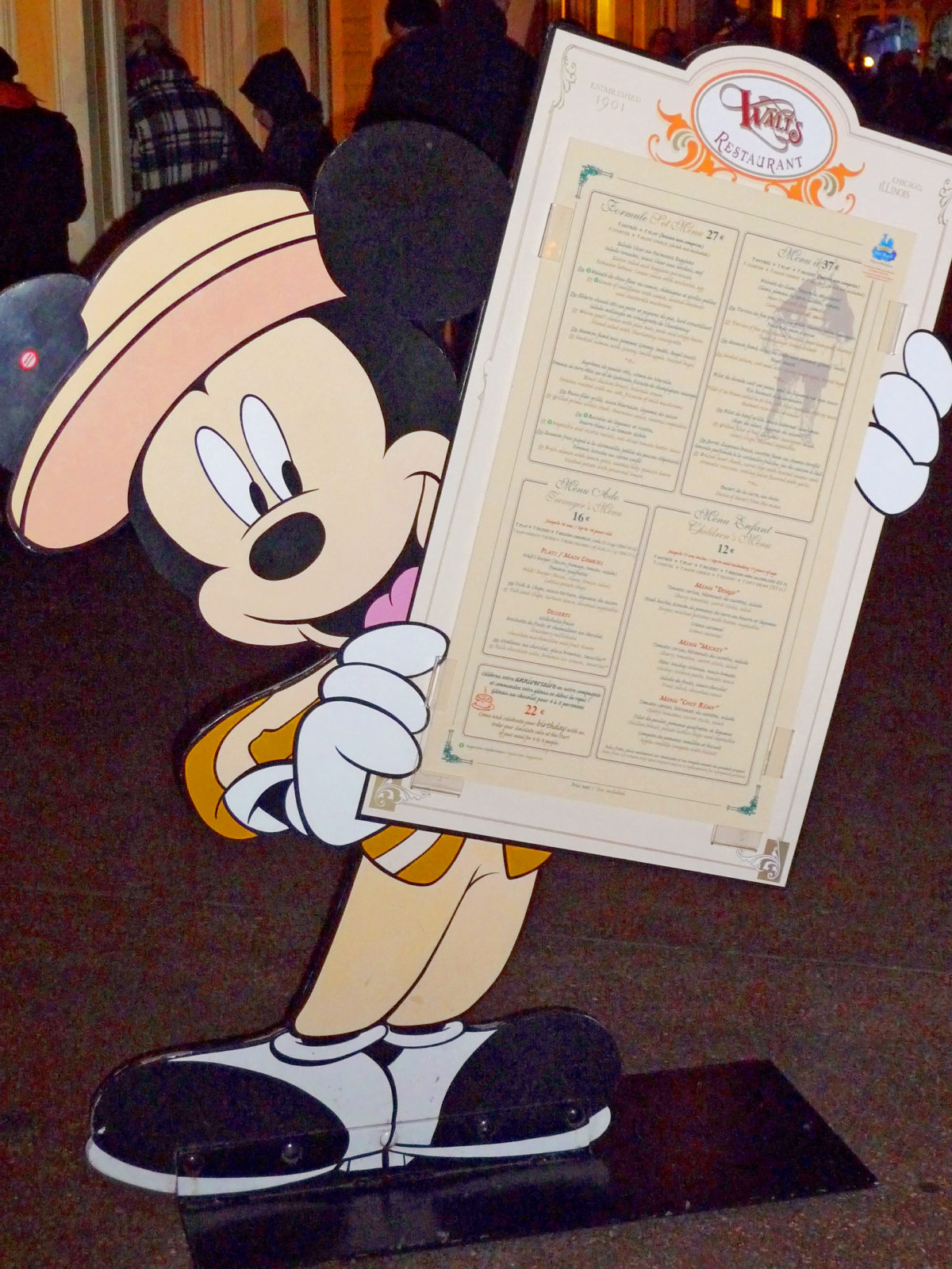 Image shows Mickey Mouse sign holding the menu for walt's restaurant in disneyland paris.