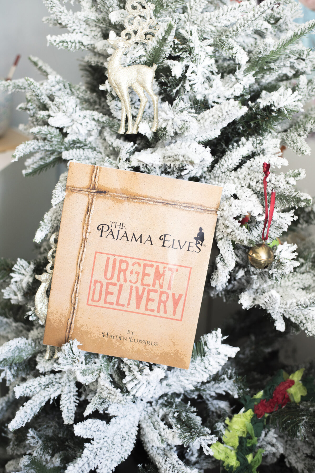 Image shows the Pyjama elves [pajama elves] book by hayden edwards in the branches of a snow covered christmas tree. Image by keep up with the jones family.