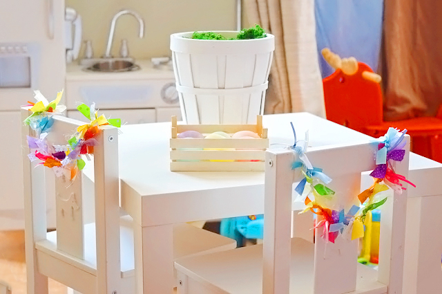 Image shows an easter table with a crate of coloured easter eggs ready for decorating.
