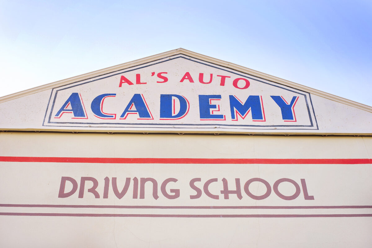 Image shows the signage on the building for Al's Auto Academy Driving School at Tornado Springs in Paultons Park.