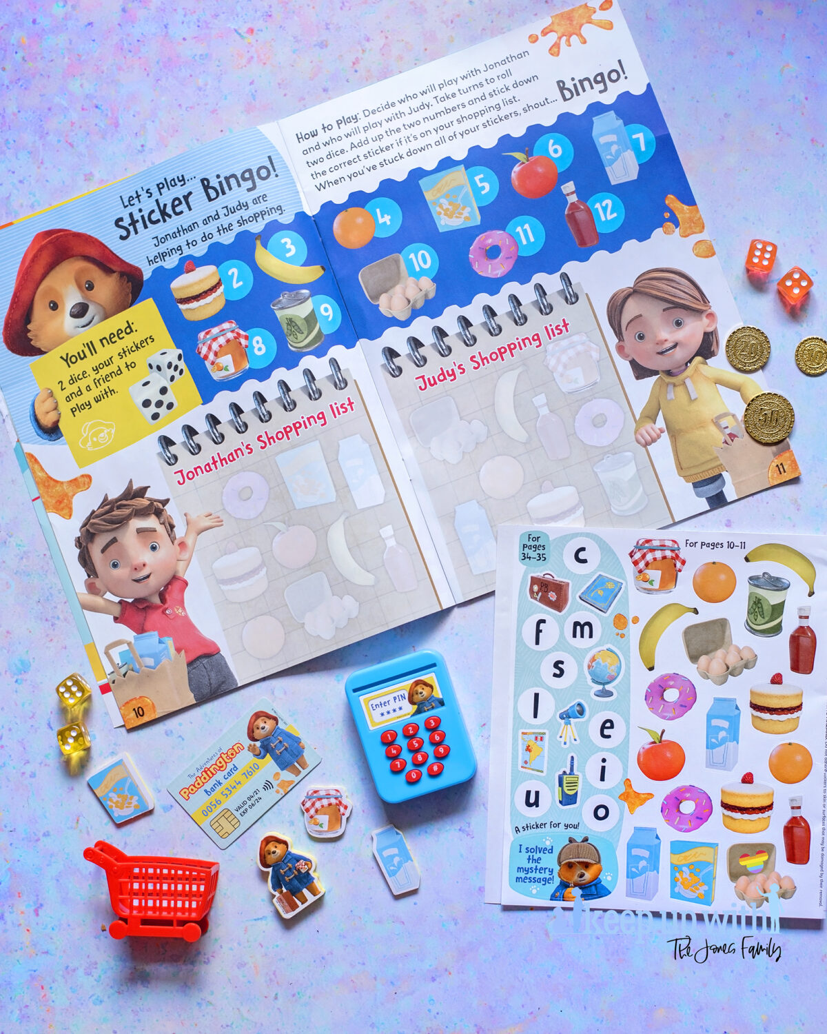 The Adventures of Paddington Bear Magazine EYFS. Photograph shows a spread of the magazine featuring a dice throwing game to calculate the cost of shopping for the under sixes.  There are coloured dice and stickers to help with the activity.