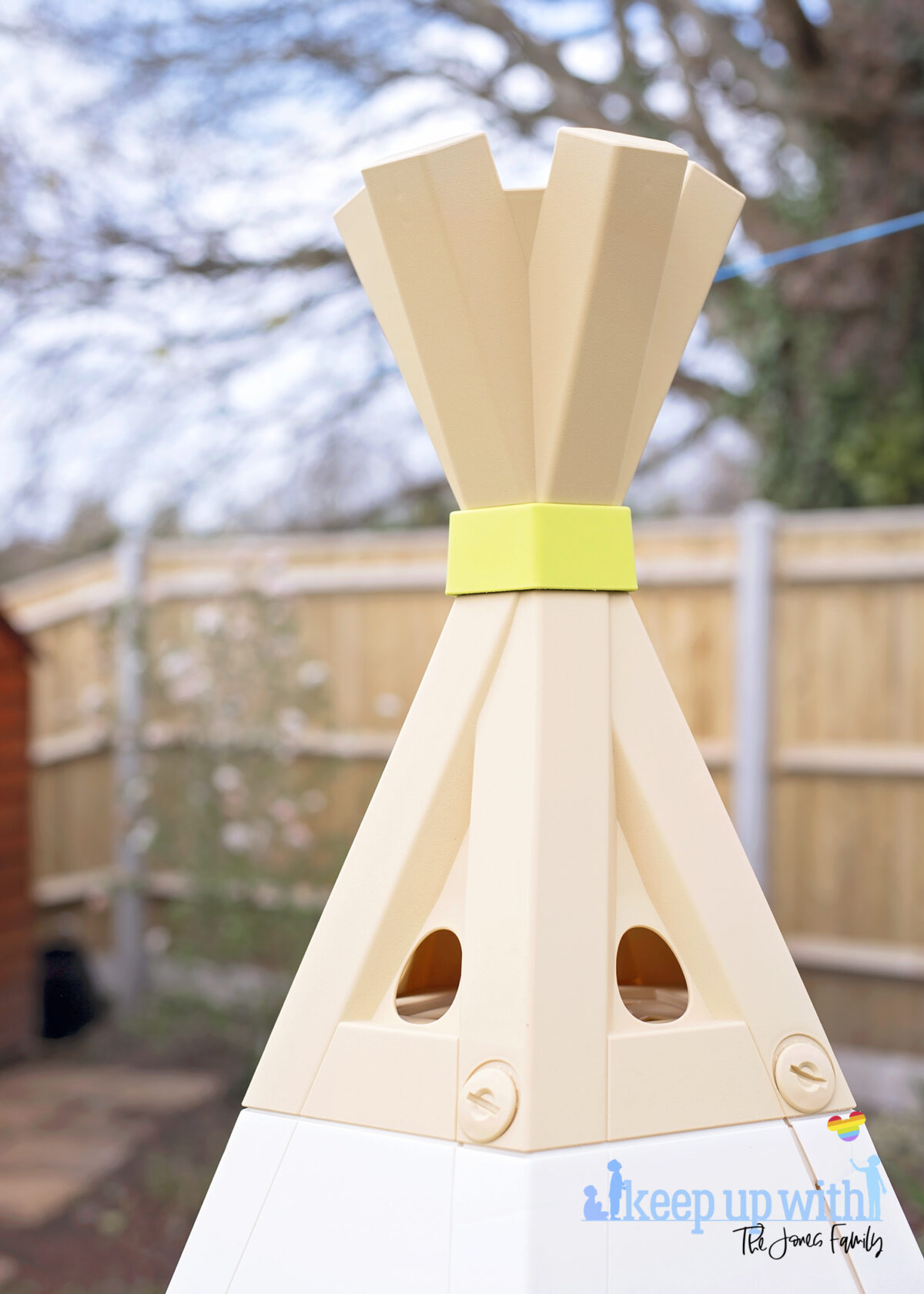 Image shows the new Smoby Teepee, available on Amazon, in the garden. The teepee is cream, white and green and the image shows the plastic teepee recreating the top part of a teepee where the wooden poles are crossed.