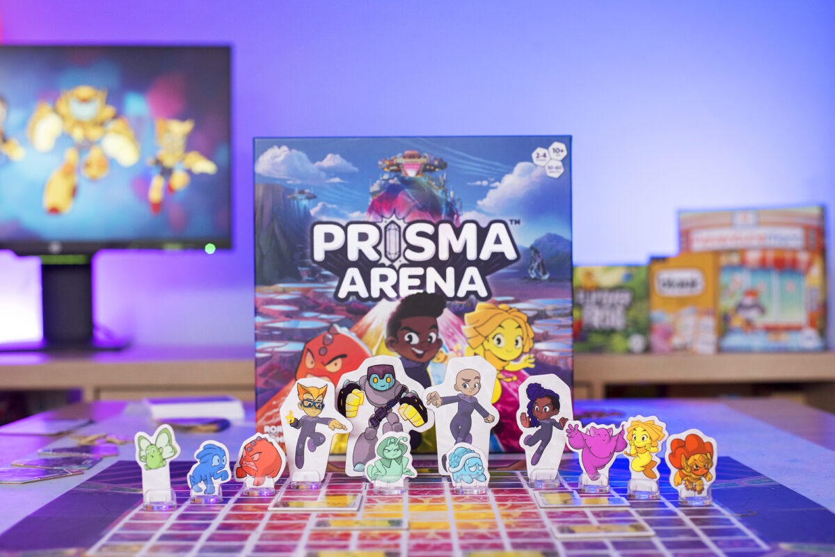 Prisma Arena Tabletop Game Box from Hub Games. Picture shows the box, board and all of the heroes and mo'kons on display.