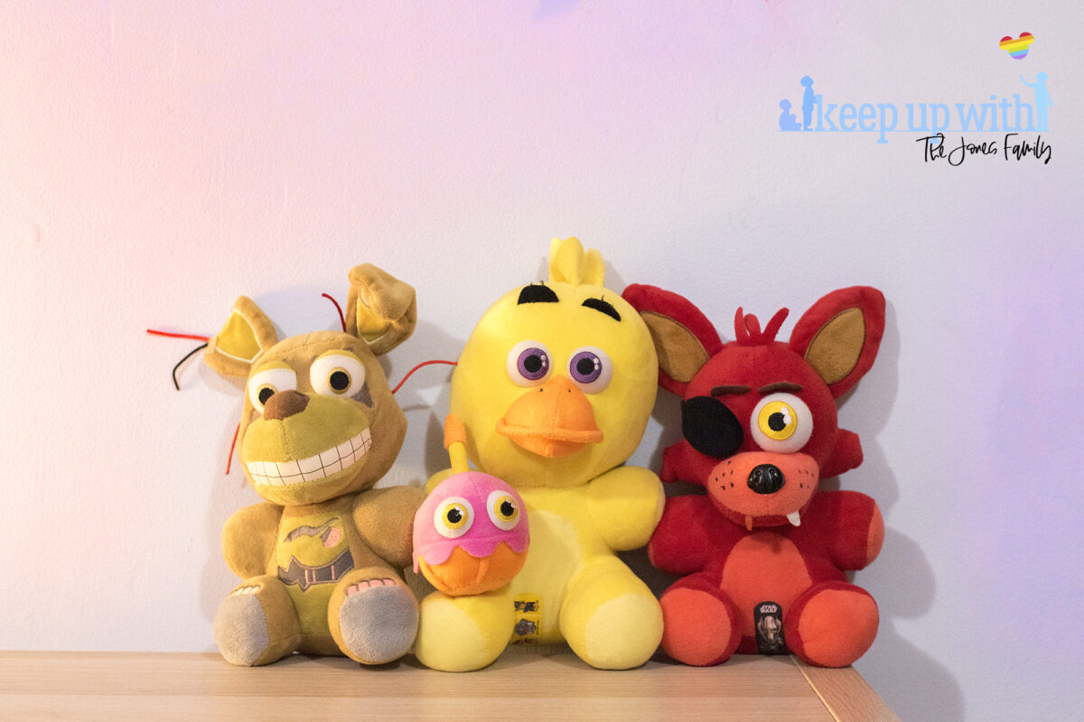 Image shows three Five Nights at Freddy's large plush toys. Foxy, Chica 
 Mr Cupcake and Springtrap. They are sat on a wooden sideboard against a pale blue wall. Image by keep up with the jones family.