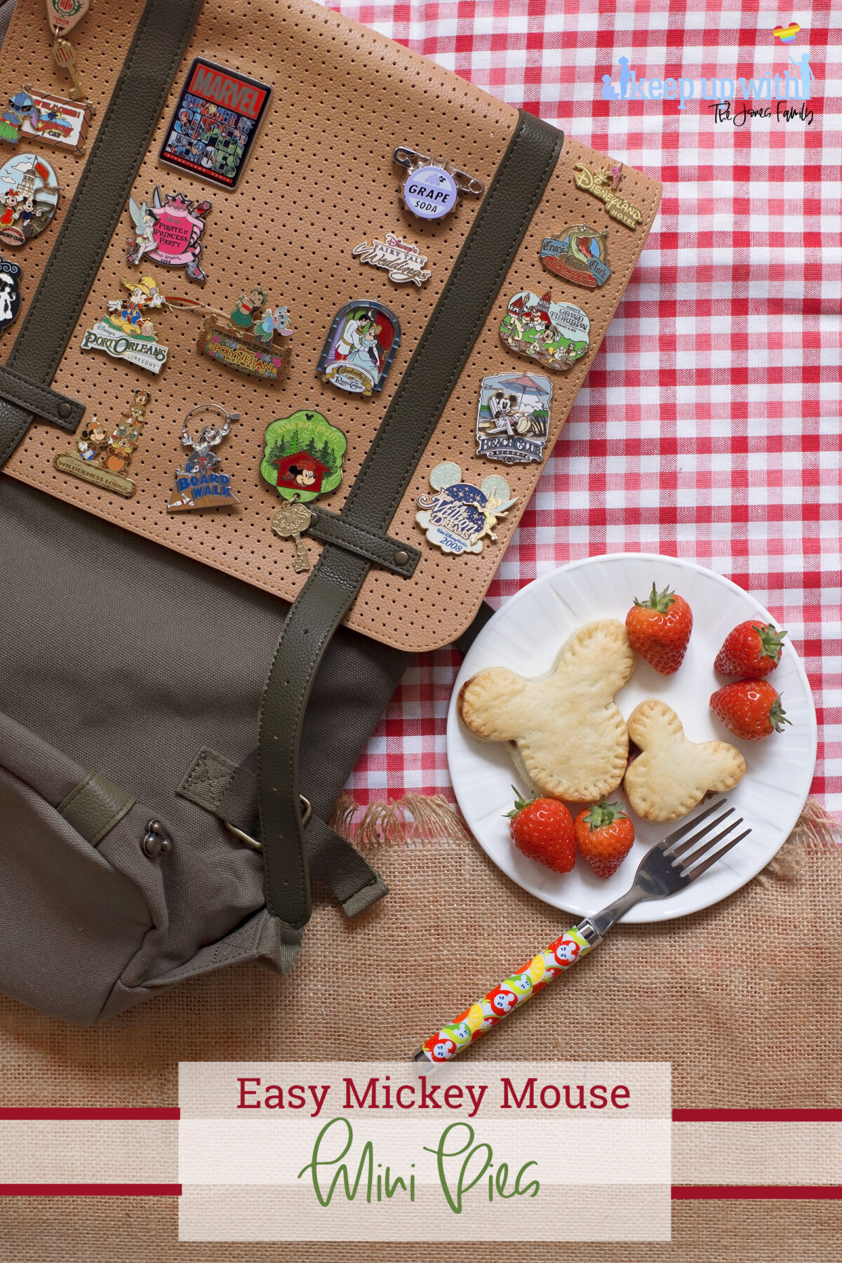 Image shows a flatlay of a red gingham checked tablecloth, overlaid with a jute burlap material with a fringe. On top is a ShopDisneyUK rucksack with many Disney pins from Disney's fairytale weddings, Port Orleans, Castaway Cay, Disneyland Hotel, Cinderellas Table and many more. Next to the bag is a white Vera Wang sideplate with two Mickey Mouse shaped shortcrust pies on. One is larger than the other. There is a ShopDisney fork balancing on the plate with a summer citrus and apples pattern on it.  The image is watermarked by Keep up with the Jones Family. 