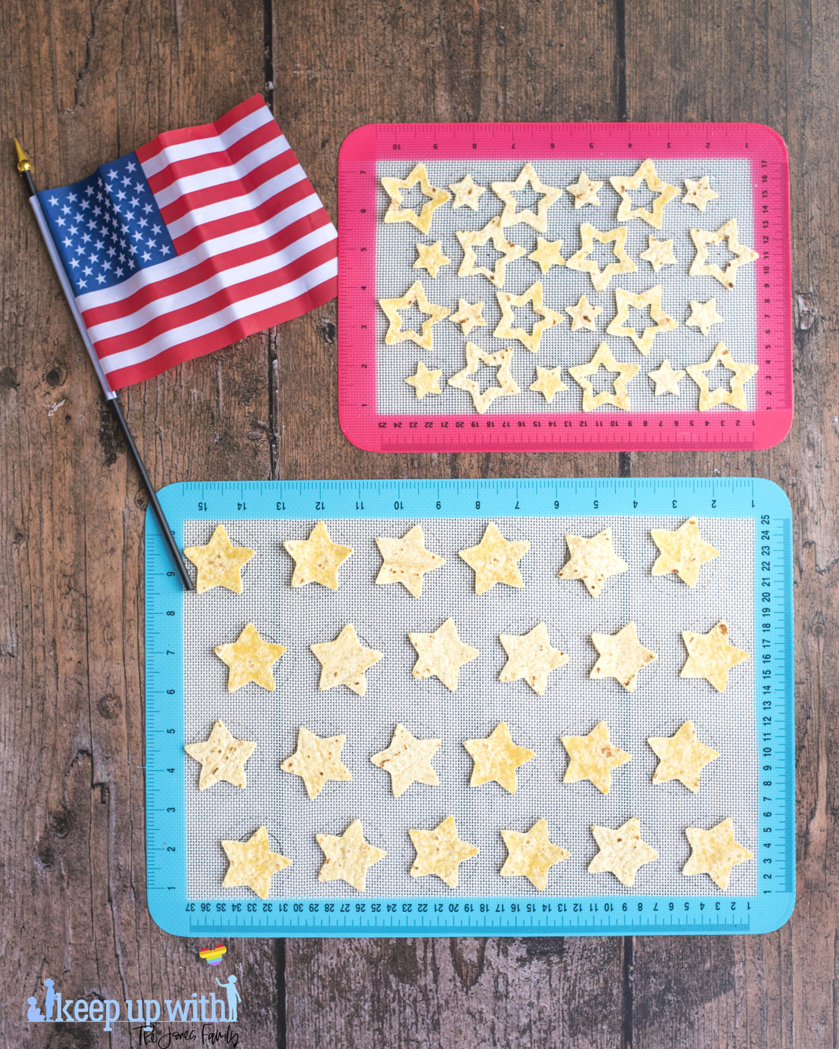 Image shows two silicone baking sheets on a dark wooden table. One is red and one is blue. On top of them are cut out star chips 'n' dip nachos from tortillas. The American flag is laid next to the baking sheets. Image by keep up with the jones family.