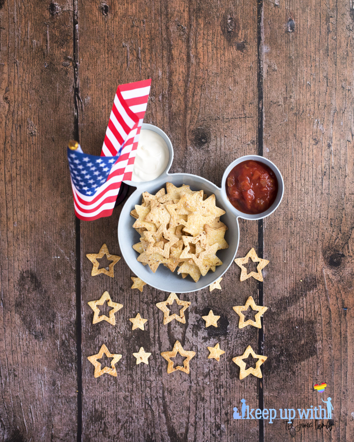 Image shows a blue bowl in the shape of Mickey Mouse suitable for chips 'n' dip. There is an American flag stood close to the bowl and inside the bowl is tomato salsa, soured cream, and star spangled nacho chips. Image by keep up with the jones family.