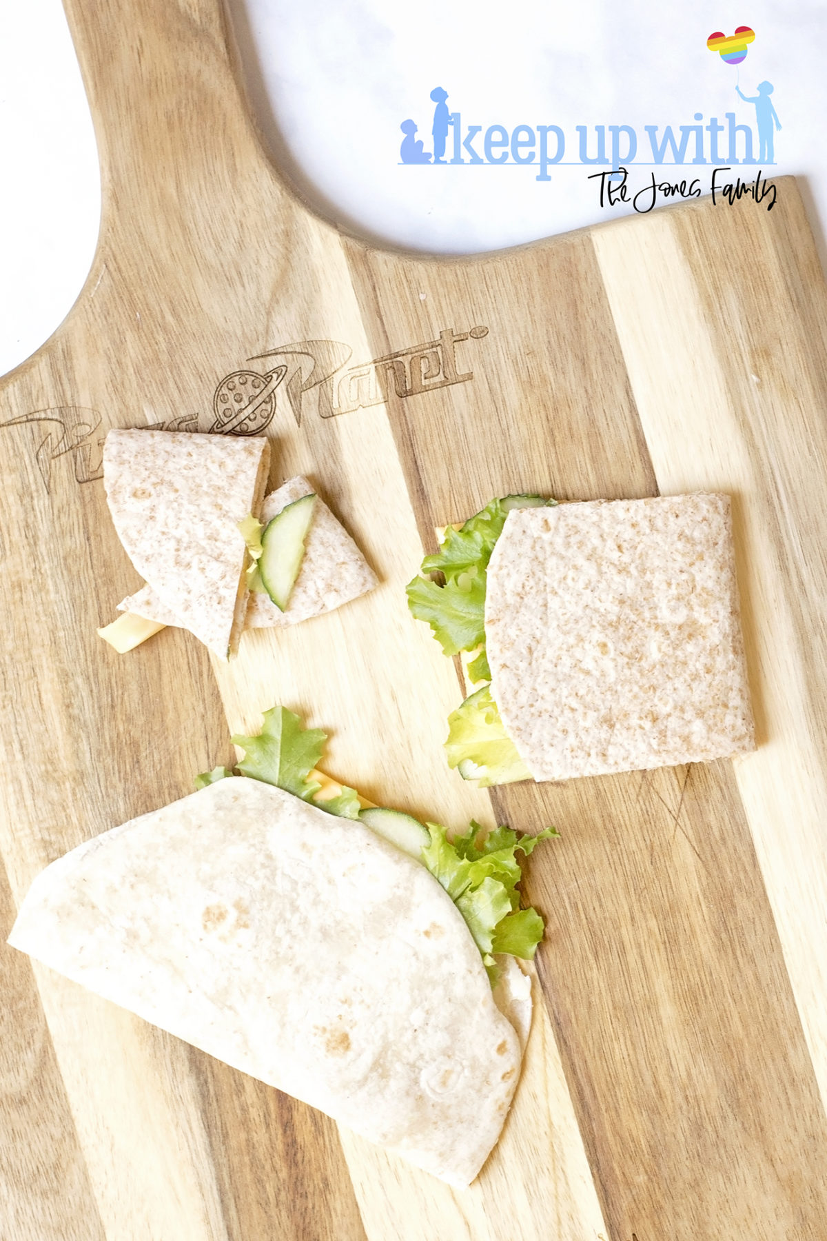 Image shows step two of how to make a book sandwich wrap. On a toy story wooden chopping board sits two wraps filled with ingredients, folder over and one of them is chopped into a booklet shape. Image by Sara-Jayne from Keep Up With The Jones Family.