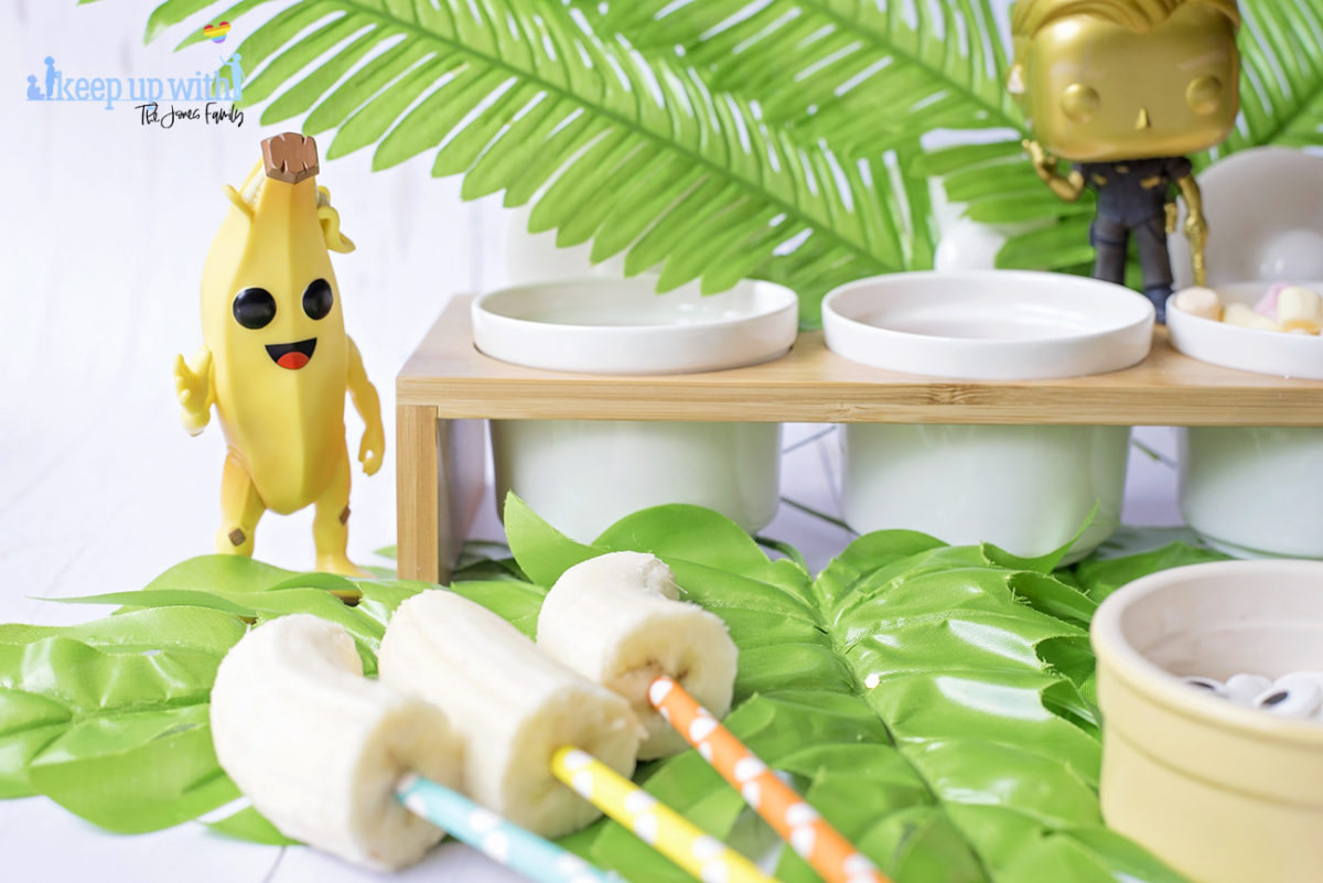 Image shows Peely’s Banana Fortnite Fondue Bar, fun food for families. A Funko Pop Vinyl Peely stands on a fondue bar next to bananas on spotted coloured straws. Image by Sara-Jayne from Keep Up With The Jones Family.