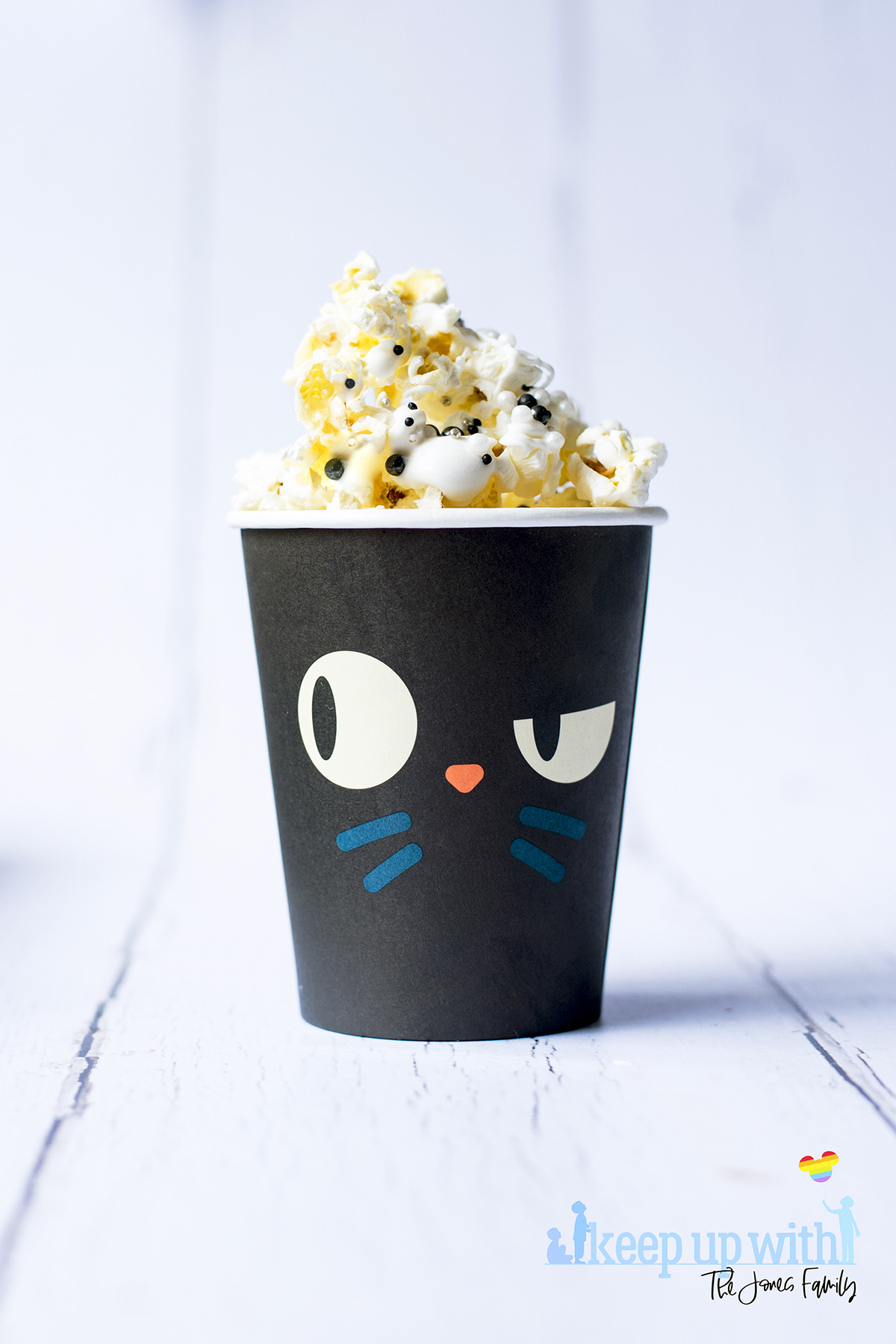 Image shows a black cat paper cup filled with disney's hocus pocus popcorn. image by keep up with the jones family.